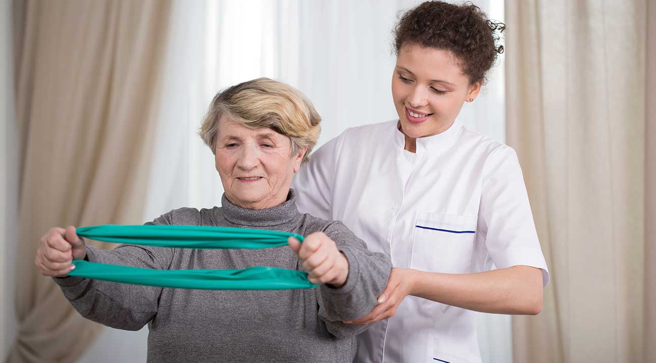 Therapist helping the elderly with resistance training